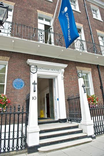 Photograph of the Chatham House depicting the main entrance and part of the first floor balcony, with the Chatham House's flag