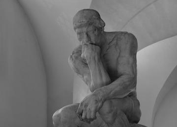 black and white photo of a statue of a man thinking