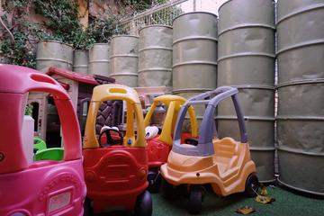 Photo of childrens' ride on toys in front of a barrier made of military barrels.