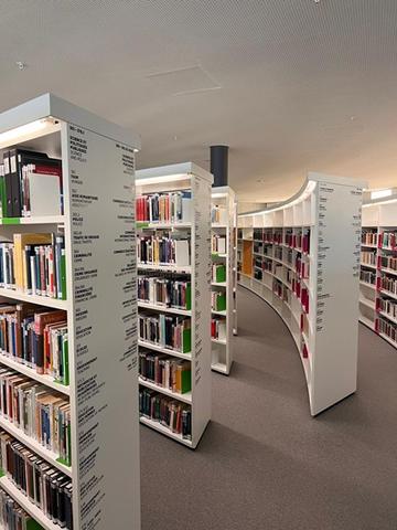 Photograph of interior space of the library, featuring white curved bookcases 