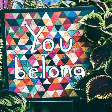 Tim mossholder zfxz xmytzs unsplash Mural painting with writing "You Belong" surrounded by plants.
