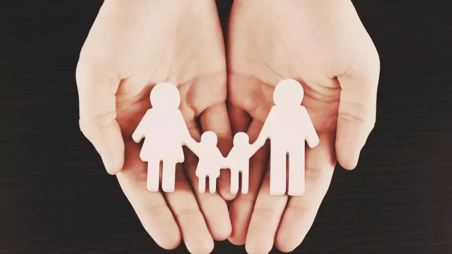 Female hands with family model on dark wooden background
