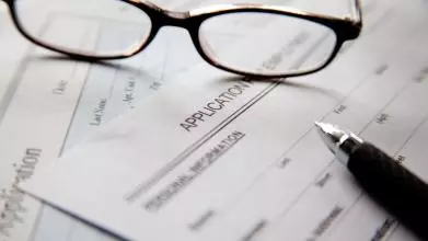 A pair of glasses abd a pen on empty application forms