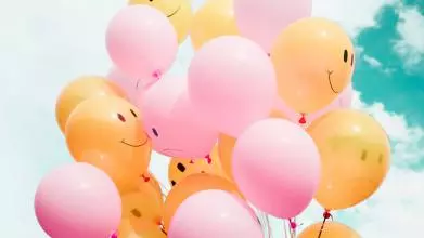low angle photo of pink and yellow ballons with sketches of facial expressions on them