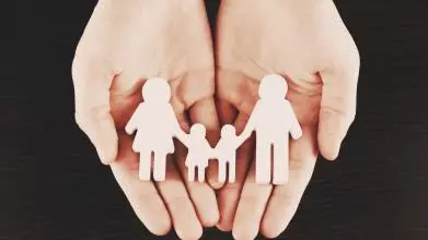 Female hands with family model on dark wooden background