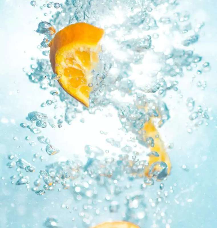 Photograph of a sliced orange fruit underwated. To be associated with freshness and summer. 